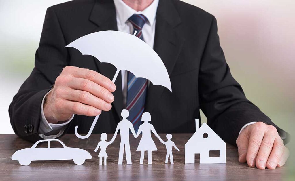 A couple reviews life insurance documents together at a kitchen table with a notepad and coffee.